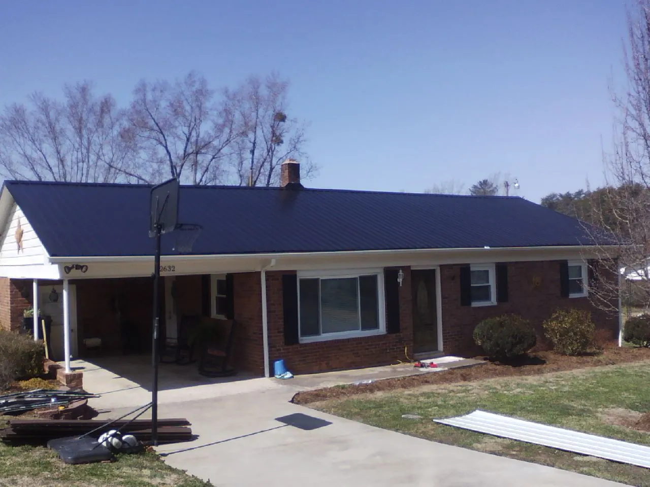 Finished dark blue metal roof on a brick ranch with a carport in Corydon
