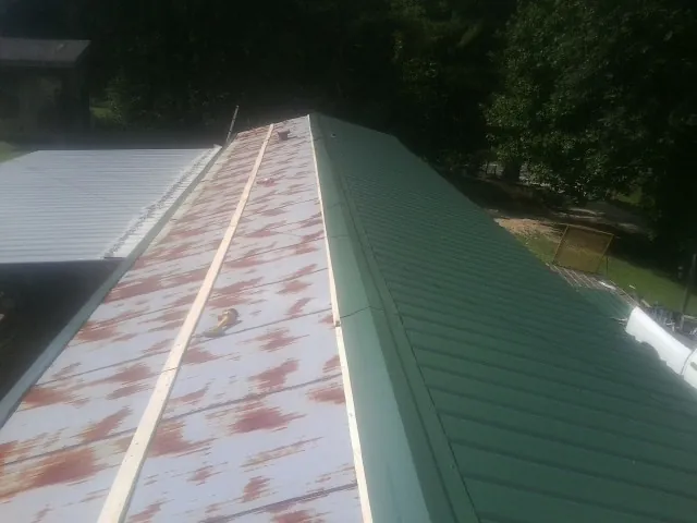 Old rusted panels beside newly installed green metal roofing — Wind Damage Roof Repair by Roofing Brothers in Corydon