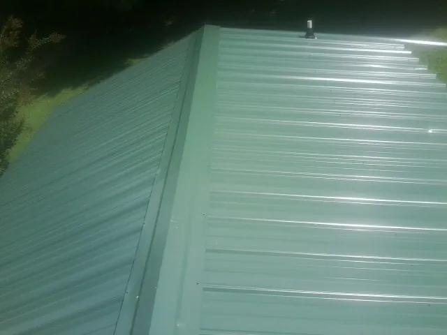 New green metal panels meeting at the ridge of a roof — Flat Roof Repair work by our crew in Corydon